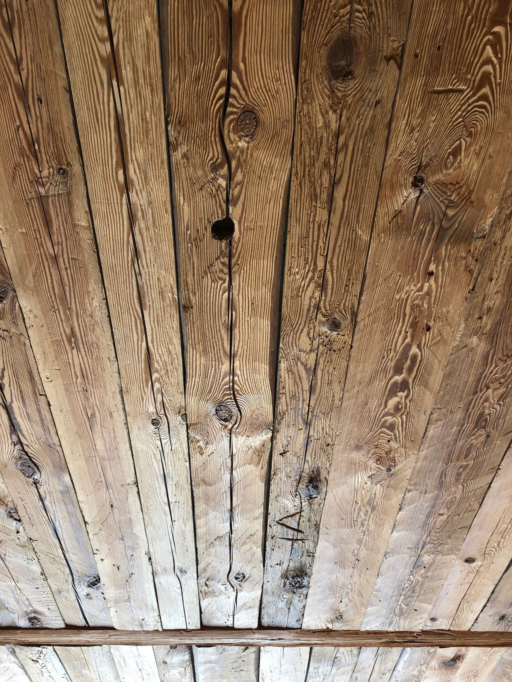 Hand-hewn reclaimed wood boards installed as rustic ceiling cladding