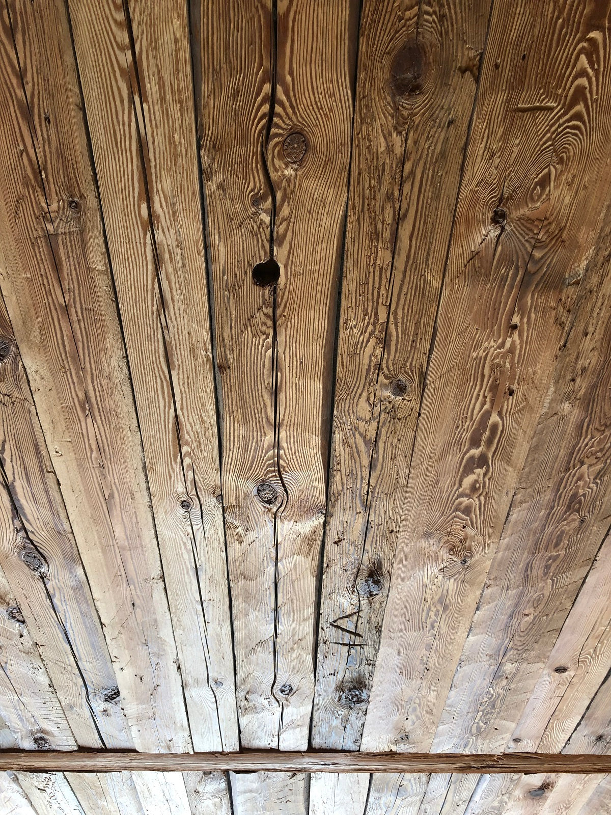 Hand-hewn reclaimed wood boards installed as rustic ceiling cladding